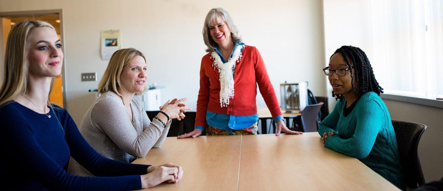 four women around a table in an office