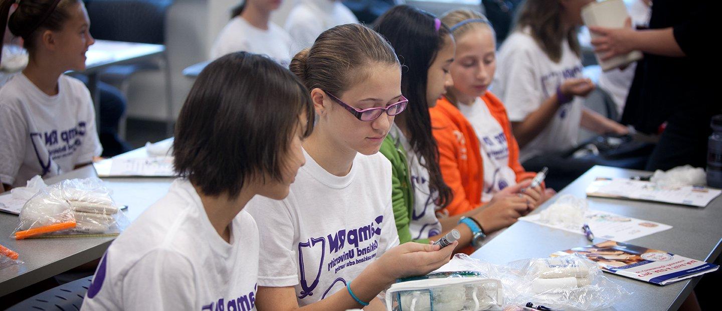 kids wearing Camp R N shirts, seated at long tables in a classroom